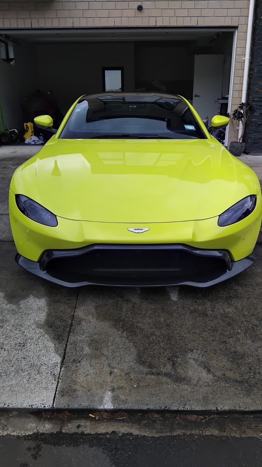 Lime green Aston Martin Vantage, front on, gloss reflecting the garage