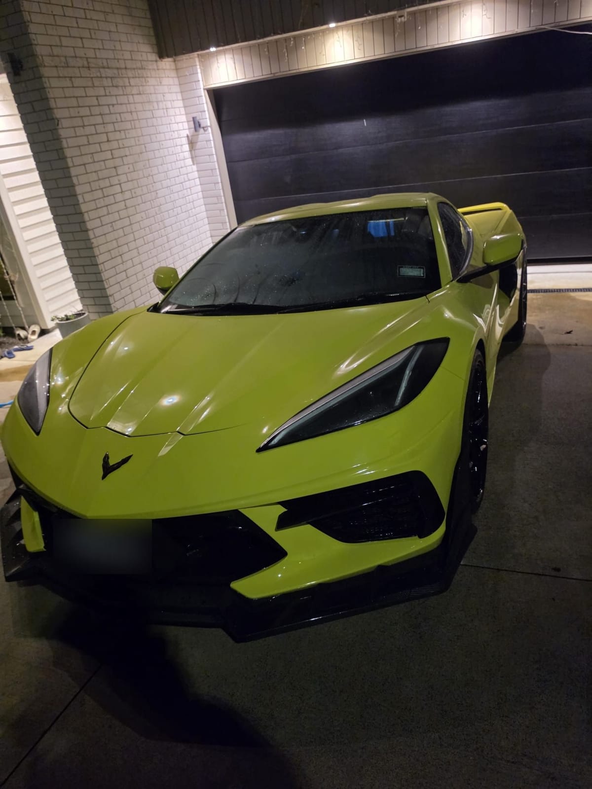 Yellow Chevrolet Corvette C8 on a driveway at night after a detail