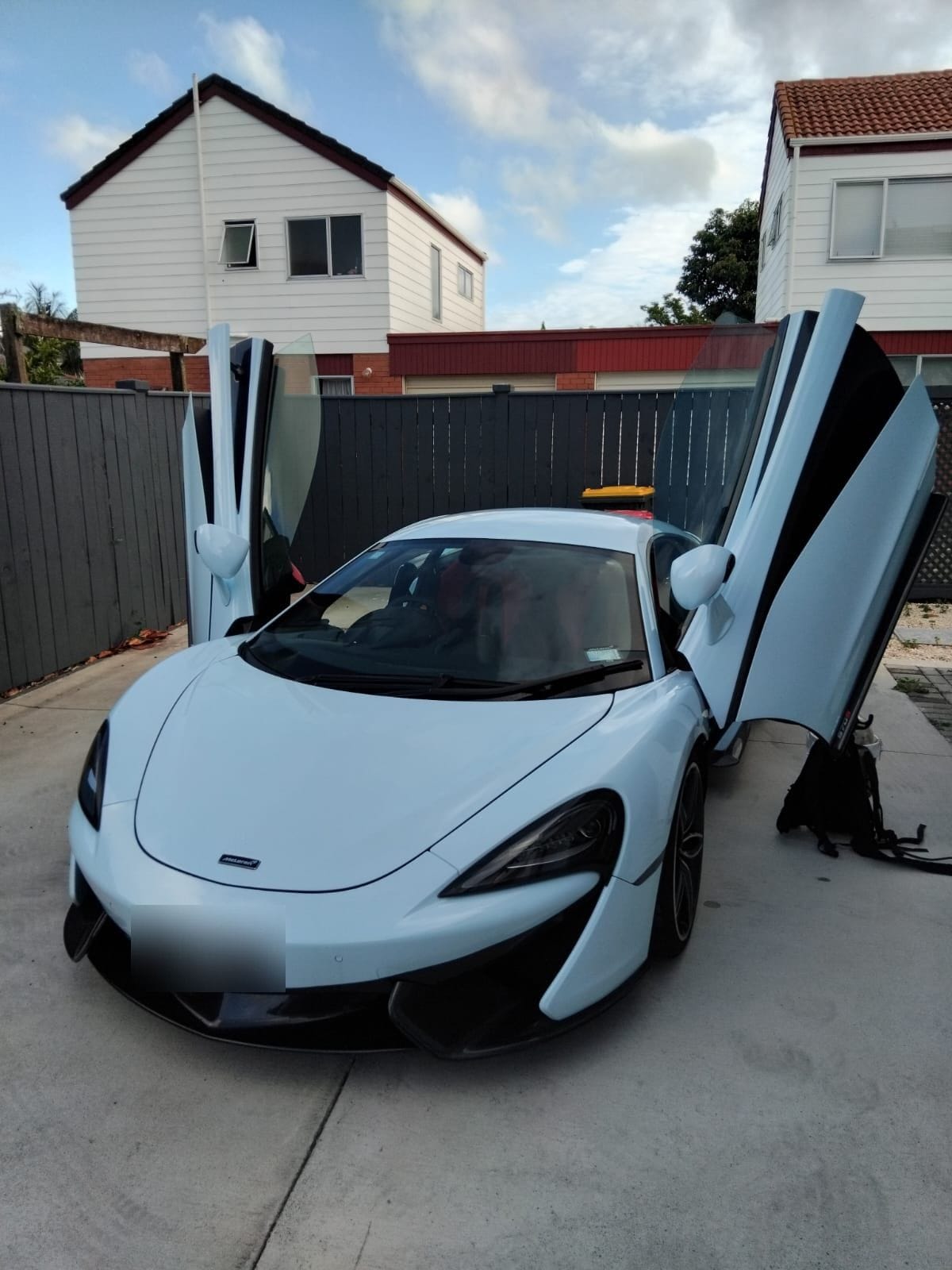 White McLaren with its dihedral doors open, detailed on a client driveway
