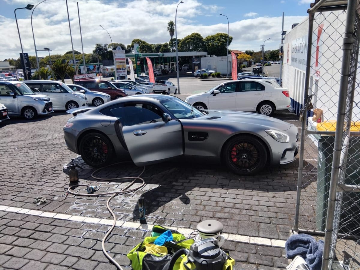 Matte grey Mercedes-AMG GT being detailed on site, kit laid out beside it