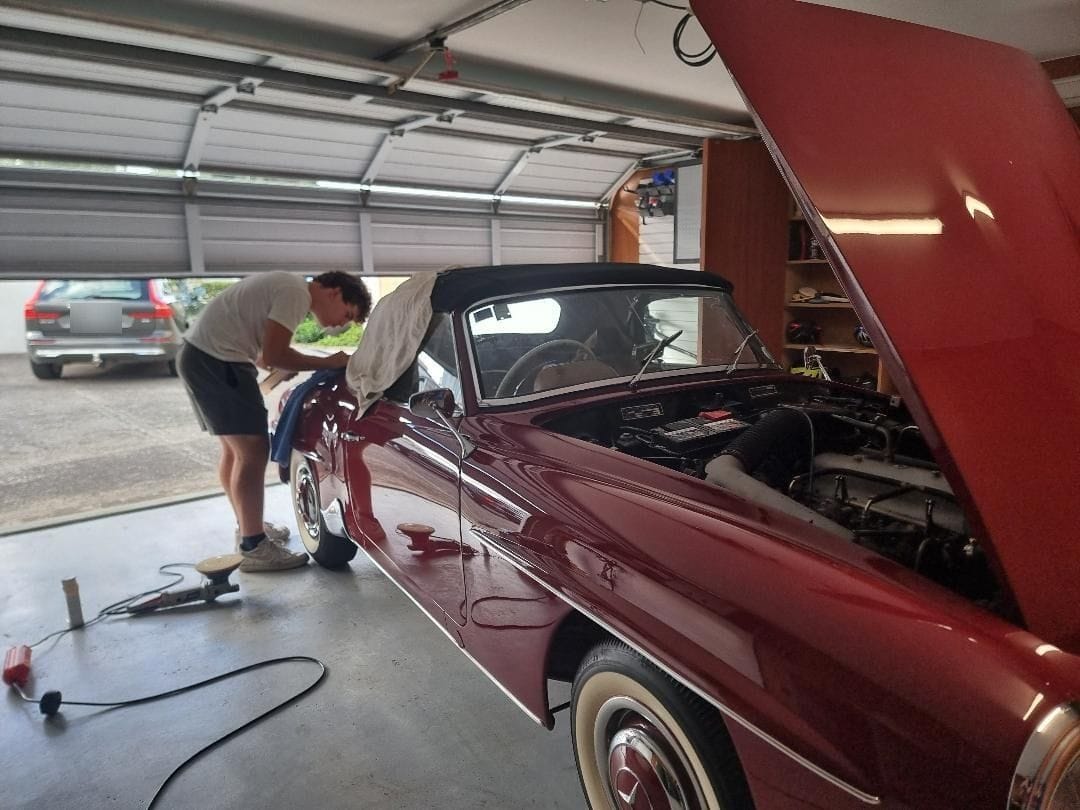 Machine polishing a classic Mercedes-Benz roadster in a client garage